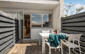 A small outdoor patio with a table and chairs, a window with a view, and a wooden fence. - Amazing apartment in Ebeltoft with WiFi (Ebeltoft)