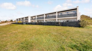 A modern multi-story building with balconies, a flat roof, and a grassy area in front. - Amazing apartment in Ebeltoft with WiFi (Ebeltoft)