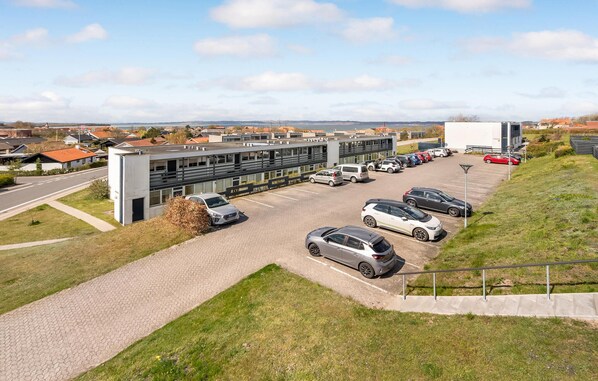 A parking lot with several cars, a building with large windows, and a clear sky. - Amazing apartment in Ebeltoft with WiFi (Ebeltoft)