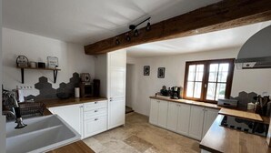 A kitchen with white cabinets, a wooden countertop, and a large window. - La Bastide des Oliviers (COTIGNAC)