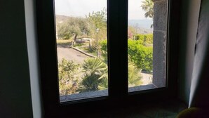 A window with a view of a landscaped garden and a distant mountain range. - A True Sicilian guesthouse with Pool on Mt. Etna, perfect for Families & Groups. (Puntalazzo)