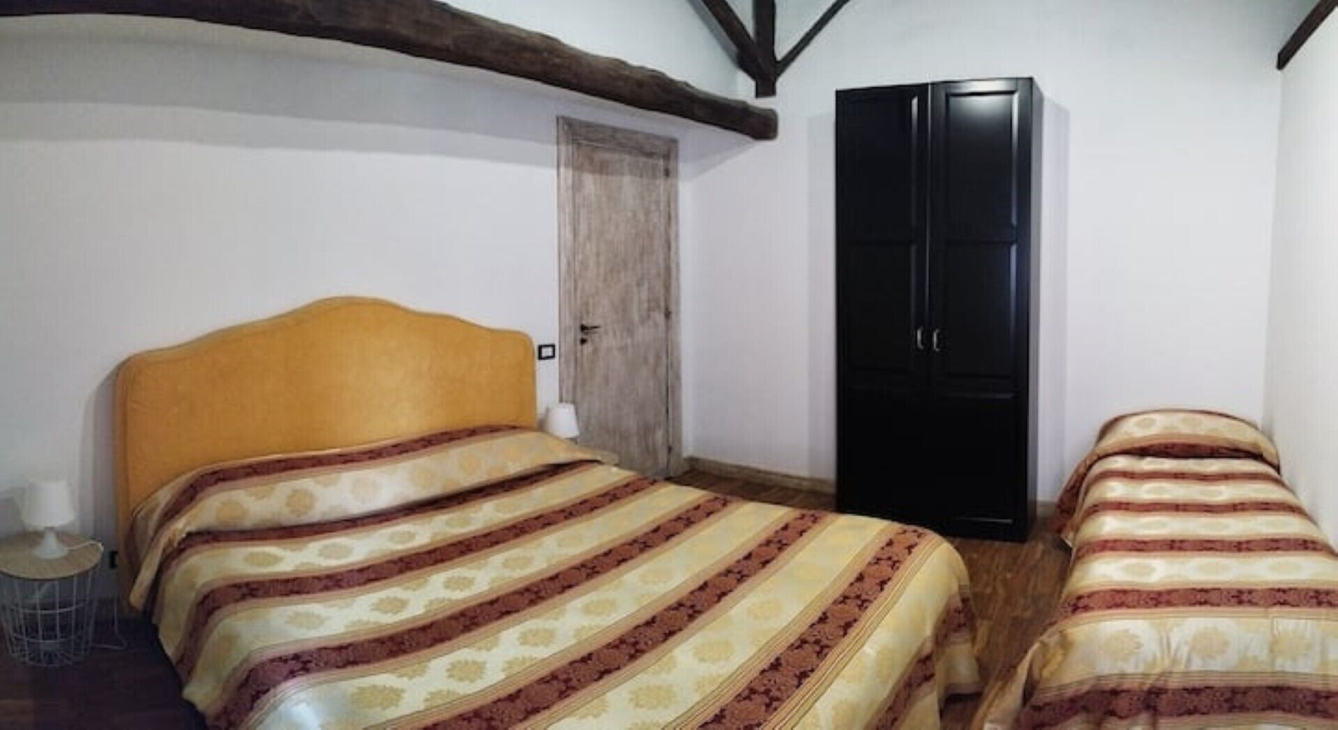 Une chambre à coucher avec un lit doté d’une tête de lit en bois, une armoire noire et une petite table de chevet.