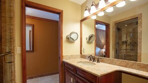 Une salle de bain avec un lavabo en marbre, un meuble-lavabo en bois et un grand miroir.