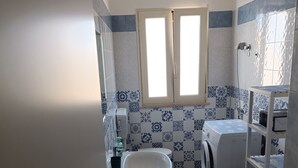 Un baño pequeño con inodoro, lavamanos y lavadora.