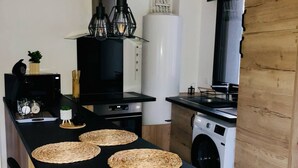 Une cuisine moderne avec un plan de travail noir, des sets de table en fibres tressées et un lave-linge encastré.