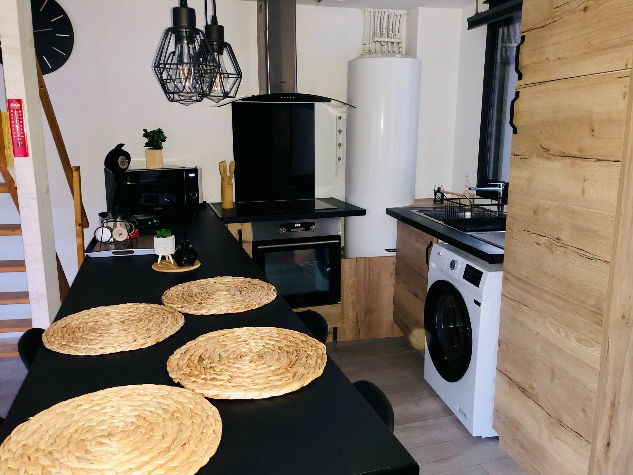 A compact kitchen with a washing machine, a microwave, and a stove.