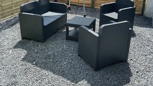 Un espace extérieur aménagé avec des meubles en osier, une table et un barbecue.