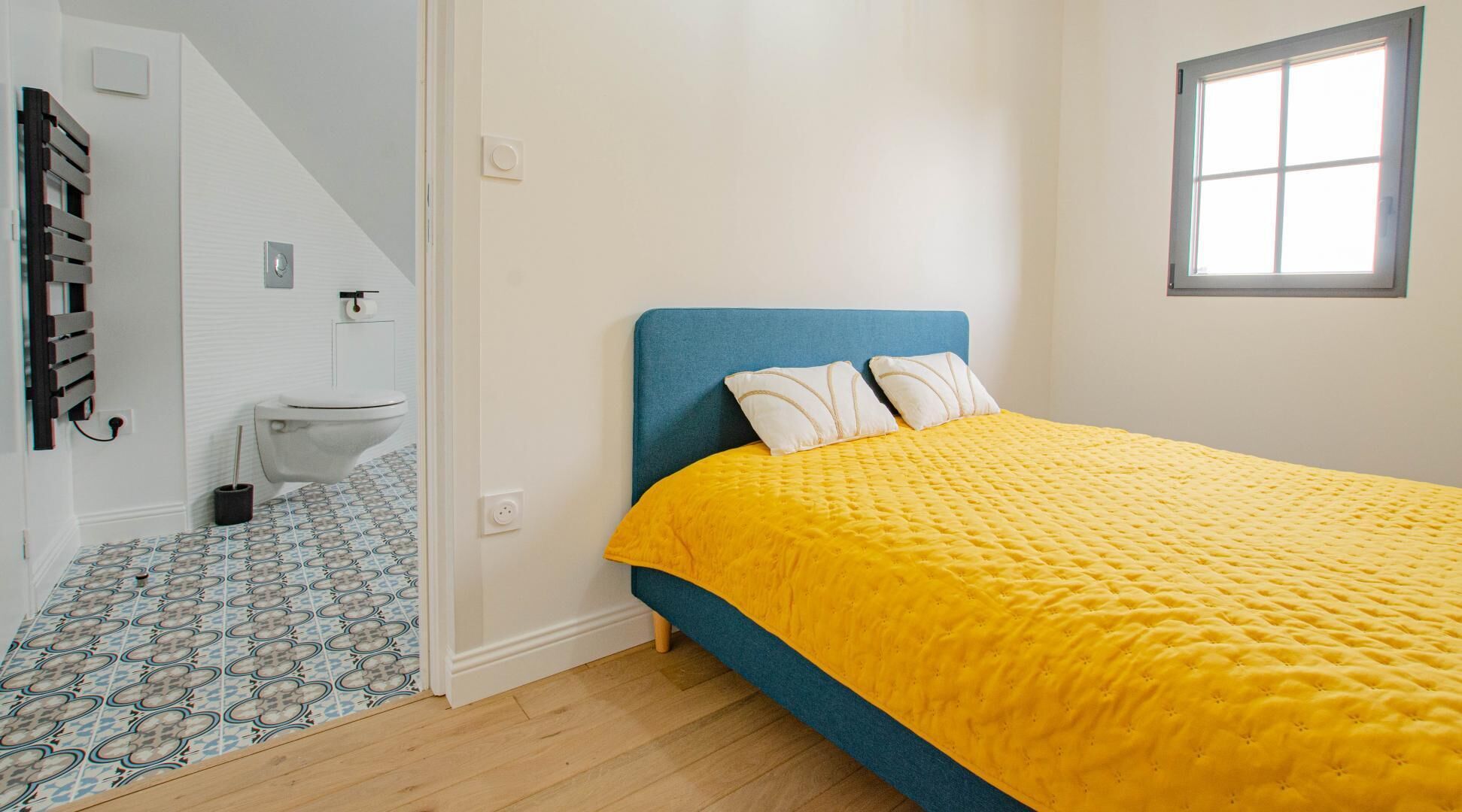 A bedroom with a bed, a window, and a bathroom.
