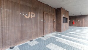 Fachada de edificio moderno con pared de metal perforado y suelo de baldosas.
