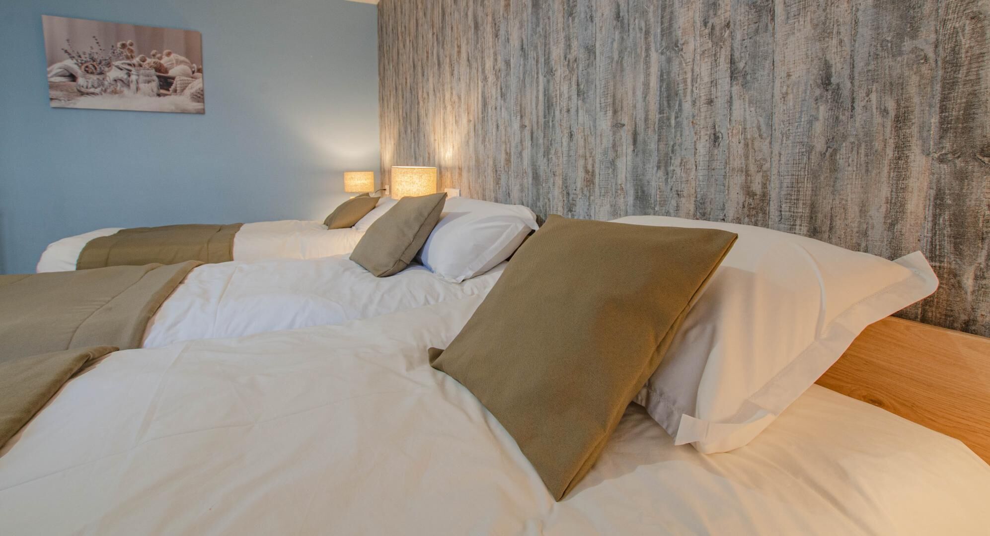 A hotel room with two beds, beige bedding, and a textured wall.