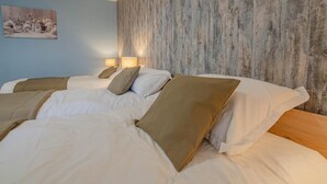 A hotel room with two beds, beige bedding, and a textured wall. - Les Bulles de l'Arce (BERTIGNOLLES)