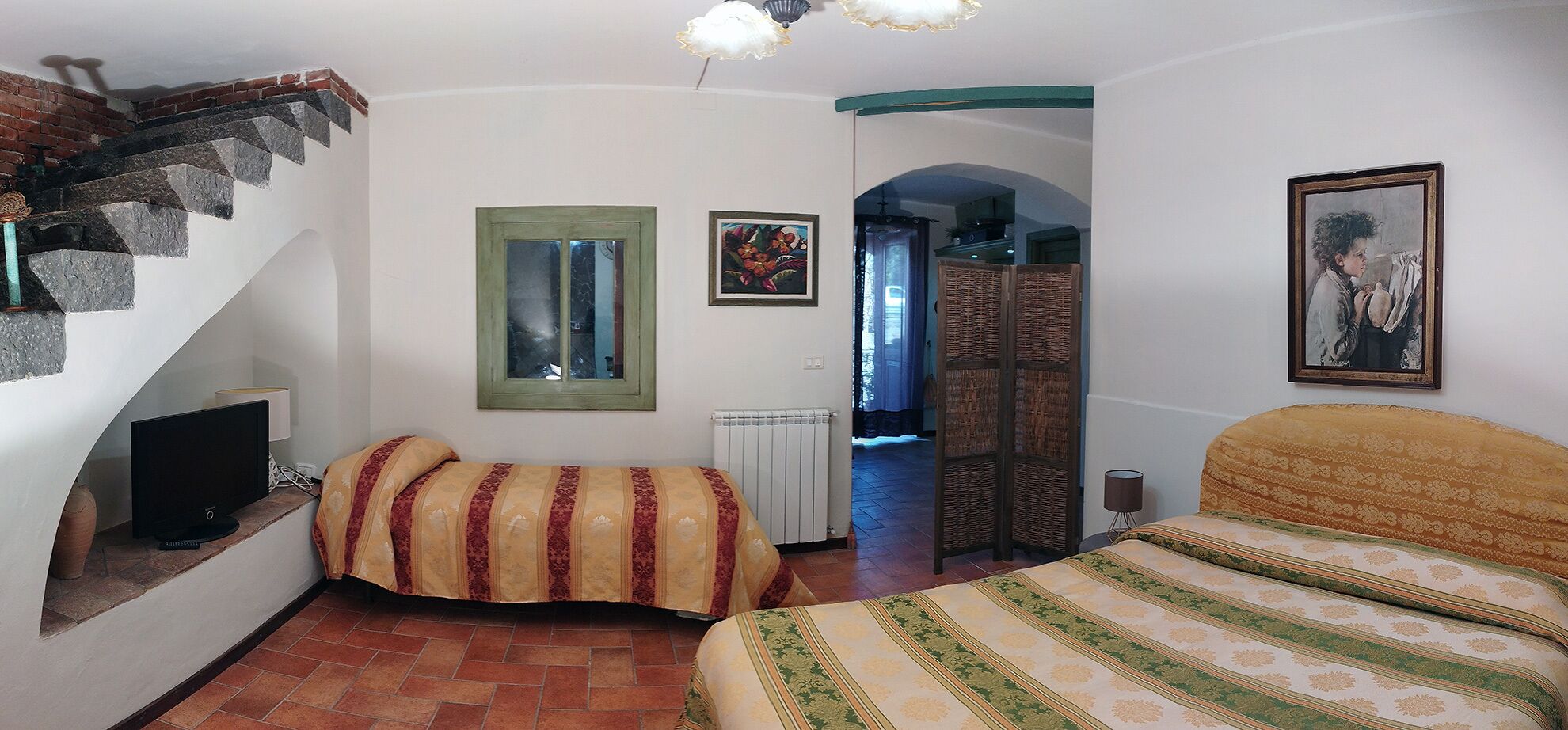Un dormitorio con cama, televisión, radiador y escalera.