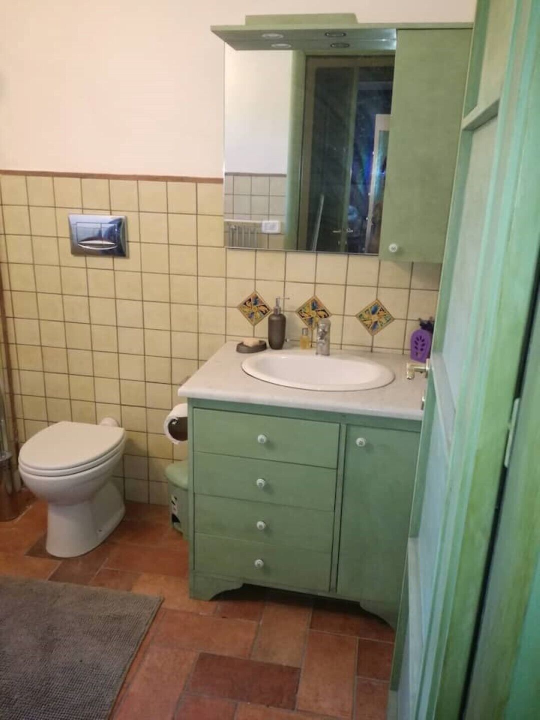 A bathroom with a toilet, a sink, and a cabinet.