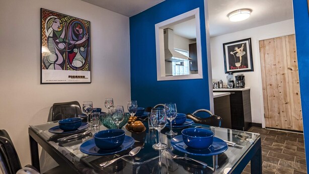 Zona pranzo con decorazioni nei colori blu e bianco, che include un dipinto di Picasso, uno specchio e una locandina incorniciata.