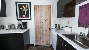 Una cucina compatta con una porta in legno, un lavandino e diversi elettrodomestici.