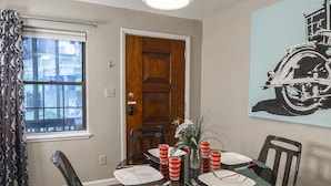 Un comedor con una mesa redonda de vidrio, sillas negras y una lámpara colgante moderna.