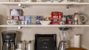 Una encimera de cocina con una cafetera, una licuadora, un bol y diversos utensilios de cocina.