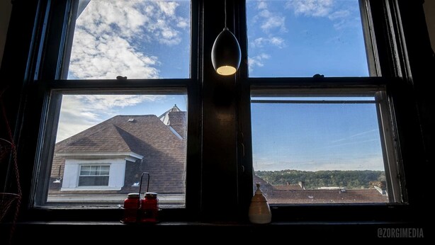 Une fenêtre donnant sur une maison et un ciel dégagé.