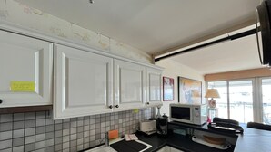 A kitchen with white cabinets, a black countertop, a microwave, and a window with a view.