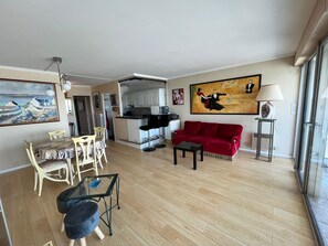 Un salon avec un canapé rouge, une table basse en verre et un coin repas comprenant une table et des chaises.