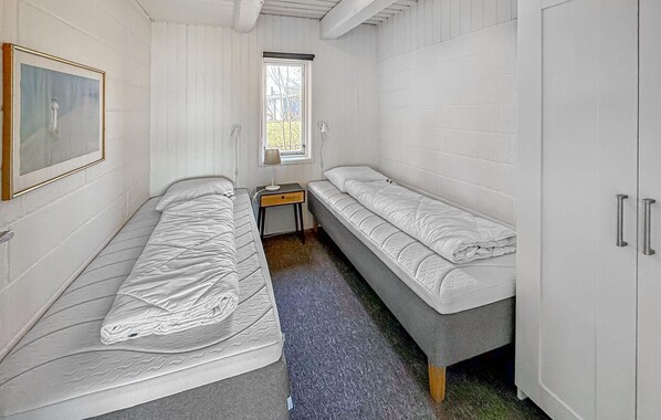 Ein Zimmer mit zwei Einzelbetten, einem kleinen Tisch, einem Fenster mit Blick und einem Schrank.