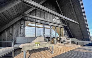 Eine Holzhütte mit geneigtem Dach, großen Fenstern und Sitzgelegenheiten im Freien.
