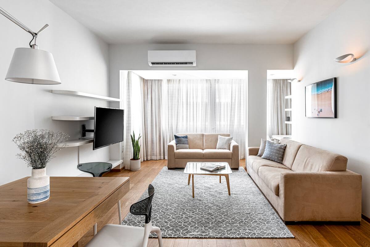 Una sala moderna con sofá, mesa de centro, televisor y objetos decorativos.