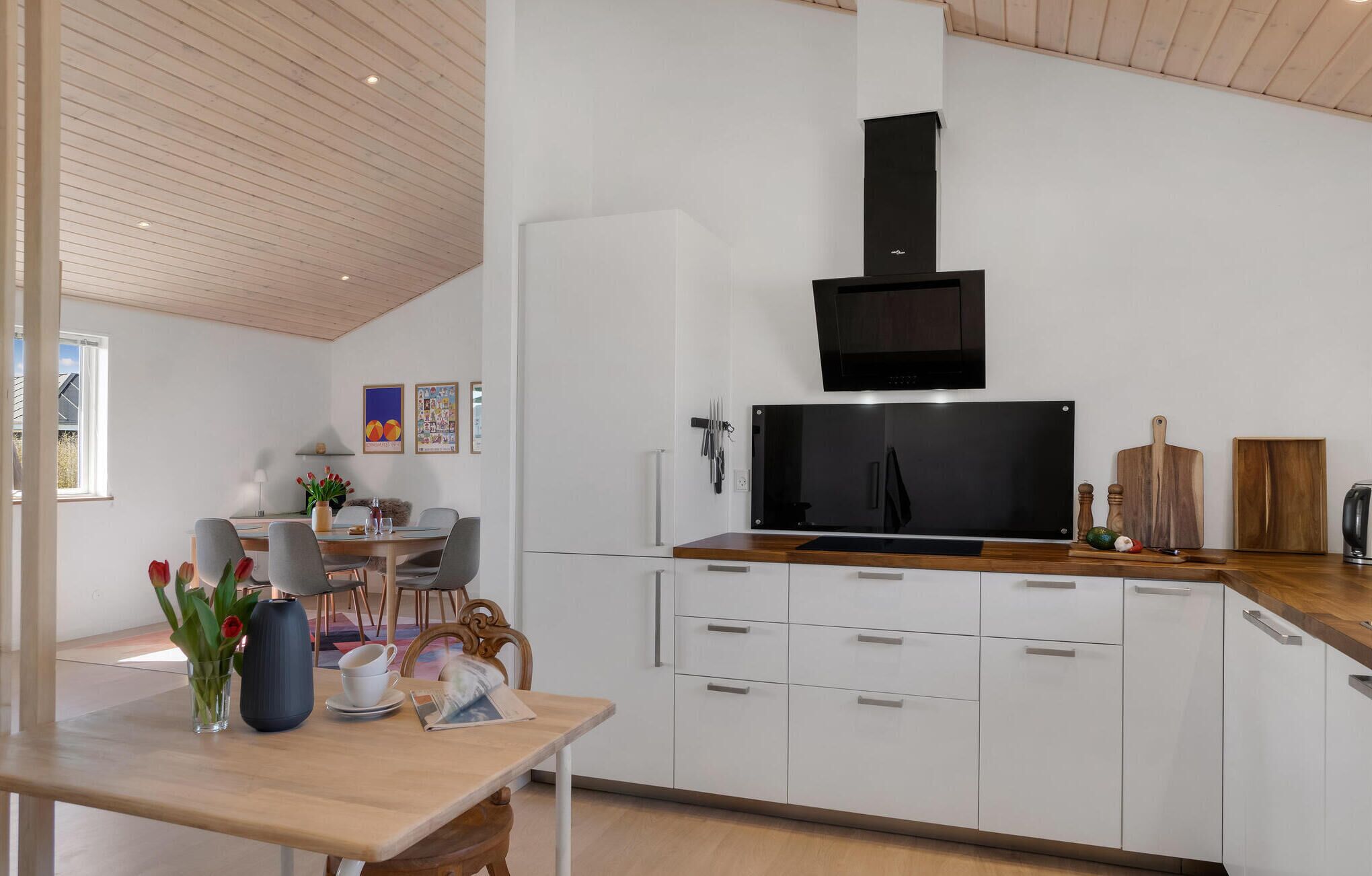 Une cuisine moderne avec des armoires blanches, une hotte noire et un plan de travail en bois.