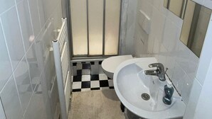 A compact bathroom with a shower, a sink, and a toilet. - Hostel Wieden (Vienna)