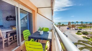 A balcony with a table and chairs, a potted plant, and a view of the beach and cityscape. - Cozy apartment in Peníscola with house sea view (Peníscola)