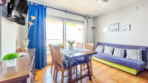 A dining area with a table and chairs, a sofa, and a potted plant. - Cozy apartment in Peníscola with house sea view (Peníscola)