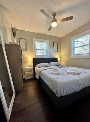 Ein Schlafzimmer mit einem Bett, Nachttischlampen, einem Deckenventilator und Fenstern.