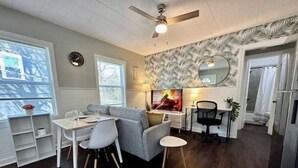 Ein modernes Wohnzimmer mit Kamin, einem Essbereich mit Tisch und Stühlen, einer Küchenzeile und einem großen Spiegel an der Wand.