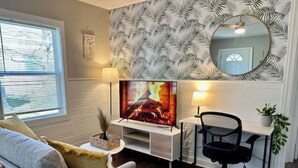 Ein Wohnzimmer mit Fernseher, Schreibtisch und Stuhl.