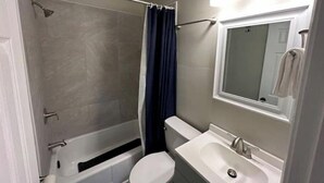 A bathroom with a bathtub, toilet, and sink. - The Red Door Cottage (Hendersonville)