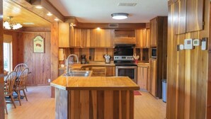 A kitchen with wooden cabinets, a central island with a sink, a stove, and a microwave.