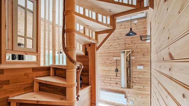 Un escalier en bois avec une rampe en corde menant à une mezzanine.