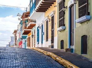 A cobblestone street lined with colorful buildings, each with distinct architectural styles and balconies. - Centrally Located Apartment + Solar Power + Sleeps 6 (Carolina)