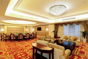 A hotel lobby with a round table, sofas, and a chandelier. - Danling Jinjiang Hotel (Danleng)