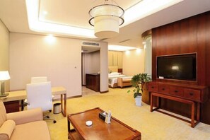 A hotel room with a television, a desk with a lamp, a sofa, a coffee table, and a bed. - Danling Jinjiang Hotel (Danleng)
