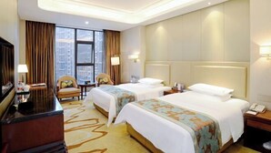 A hotel room with two beds, a desk, a chair, a TV, and a large window with curtains. - Danling Jinjiang Hotel (Danleng)