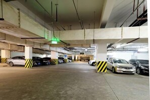 A multi-level underground parking garage with several cars parked and a green exit sign. - Danling Jinjiang Hotel (Danleng)