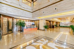 A spacious lobby with a marble floor, a reception desk, and a large plant.