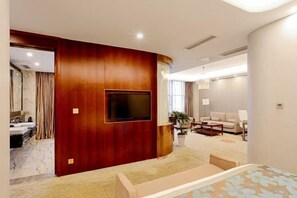 A modern hotel room with a wooden accent wall, a flat-screen TV, a sofa, and a bed. - Danling Jinjiang Hotel (Danleng)