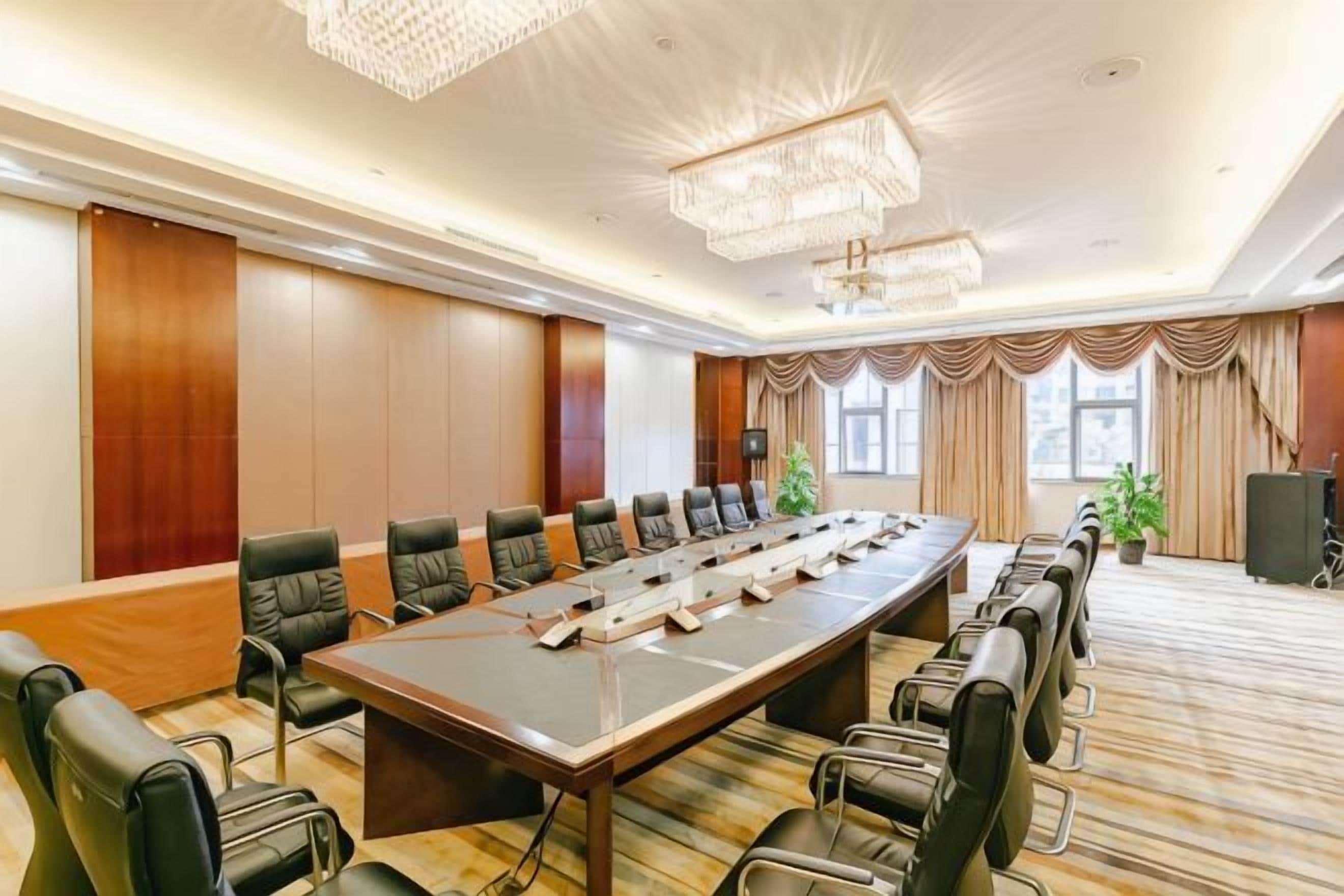 A conference room with a long table, multiple chairs, and a chandelier.