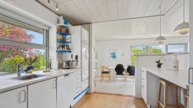 Una cocina moderna con armarios blancos, un lavamanos y una ventana con vistas a un jardín.