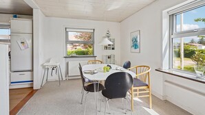 Una cocina luminosa con una mesa de comedor, sillas y un ventanal con vistas a zonas verdes.