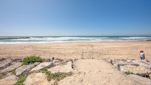 A beach with a rocky foreground and a clear view of the ocean. - GuestReady - Sunshine at Costa da Caparica (Costa da Caparica)