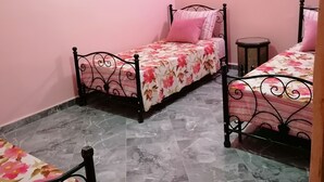 Un dormitori amb dos llits, una taula petita i parets roses.