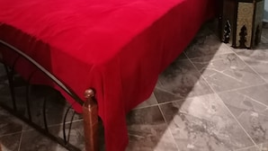 Una habitació amb un llit, una taula rodona petita i una presa de corrent.